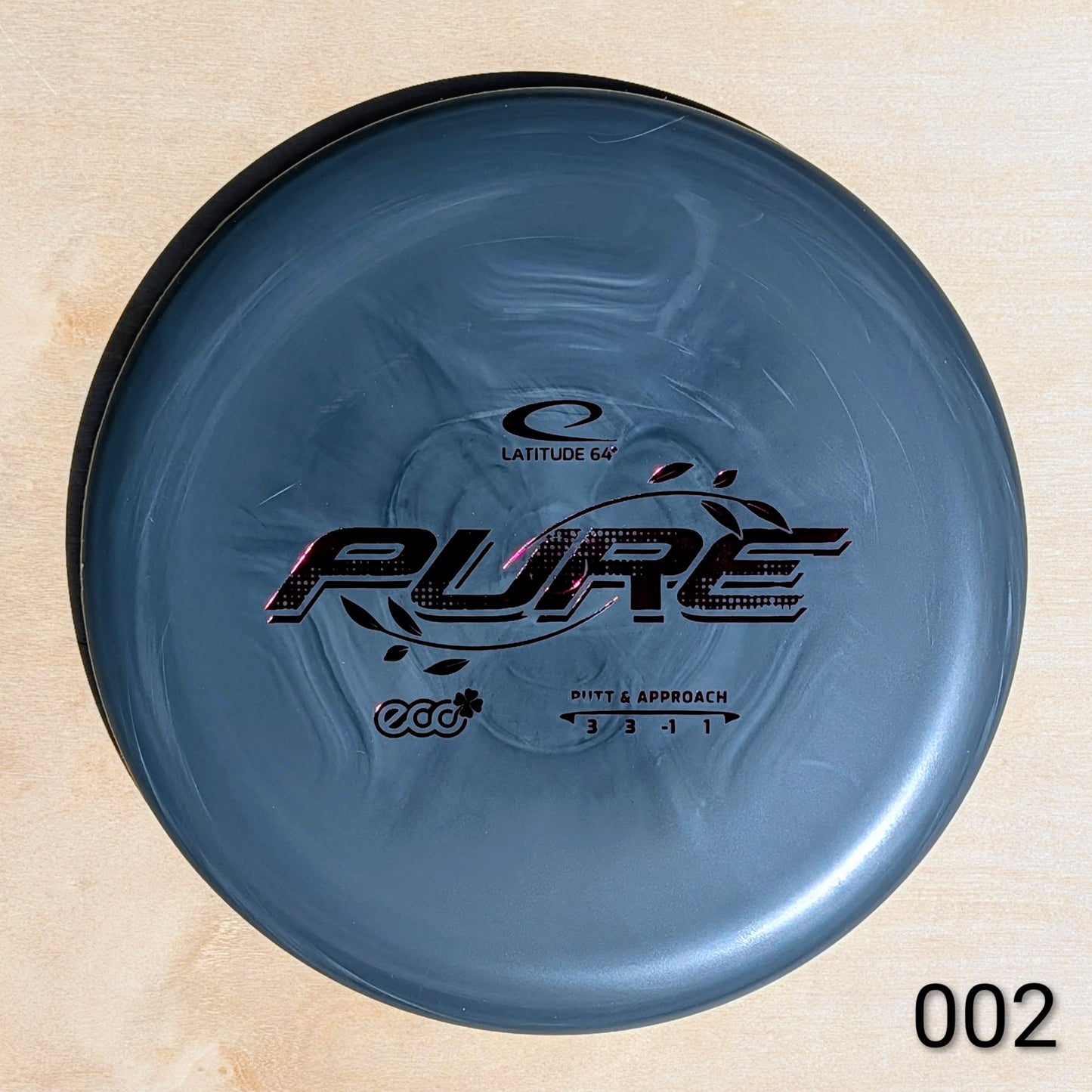 Blue disc golf disc with 'Latitude 64' and 'Pure' branding on a wooden surface.