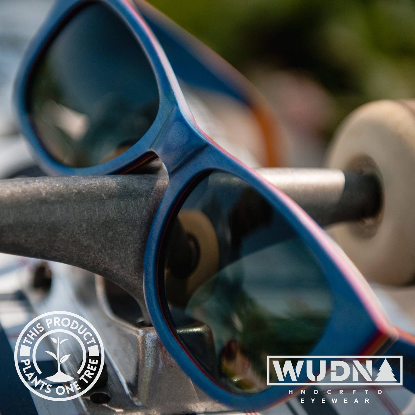 Escalator blue Recycled Blue sunglasses with a blurred background, featuring WUDN logo.