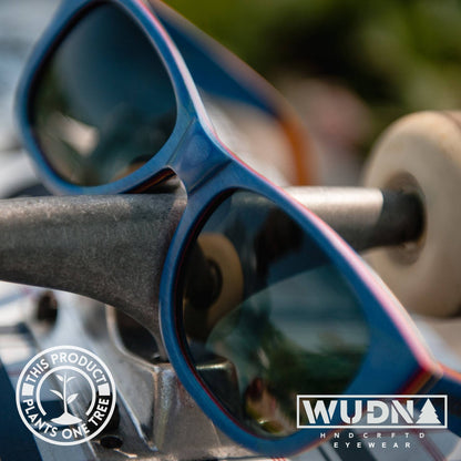 Escalator blue Recycled Blue sunglasses with a blurred background, featuring WUDN logo.