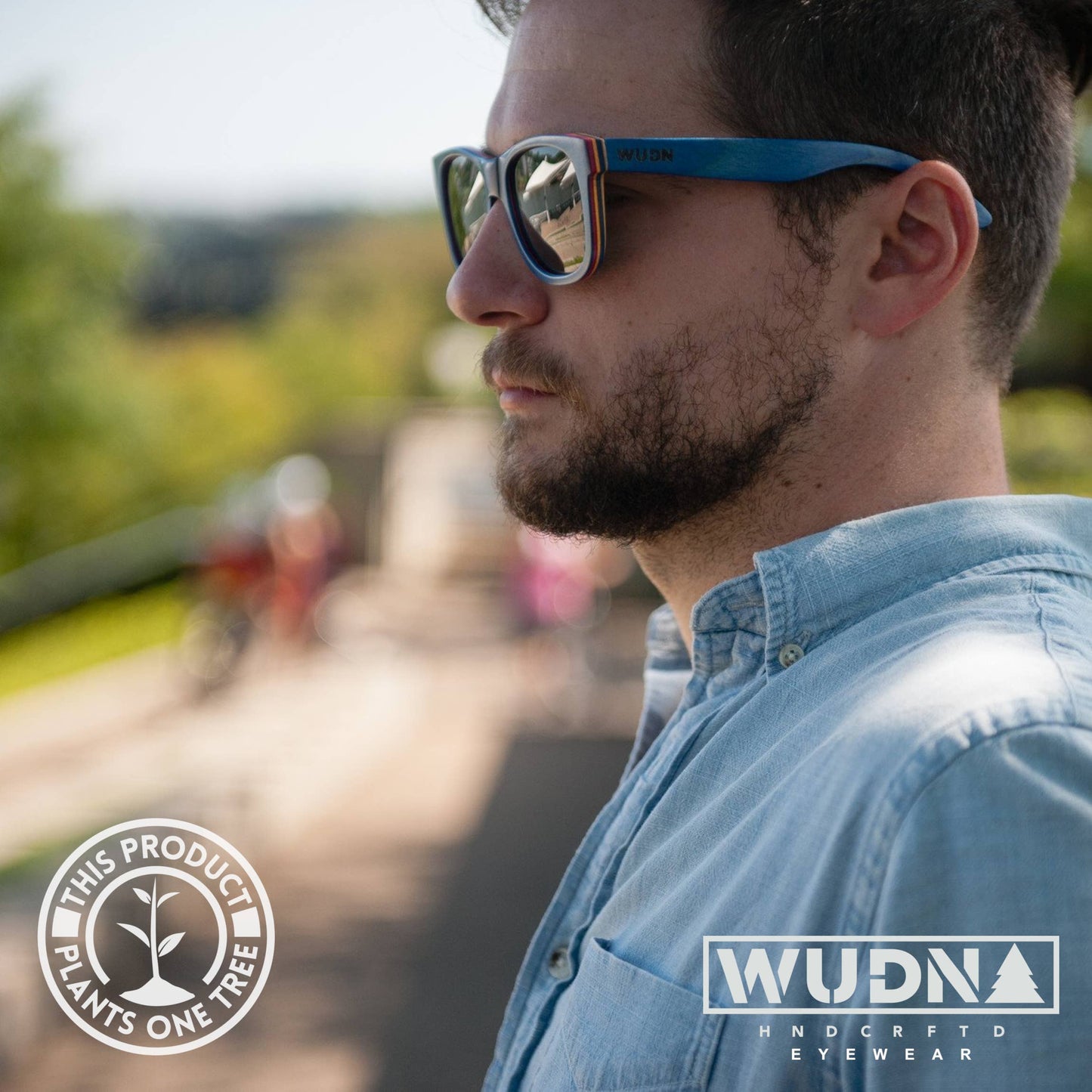 Escalator blue Recycled sunglasses with a blurred outdoor background, featuring WUDN eyewear branding.