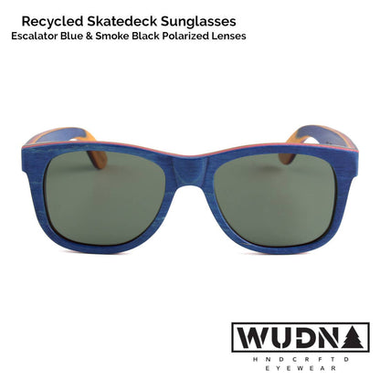 Escalator blue Recycled skatedeck sunglasses with blue frame and dark lenses on a white background, featuring WUDN logo.