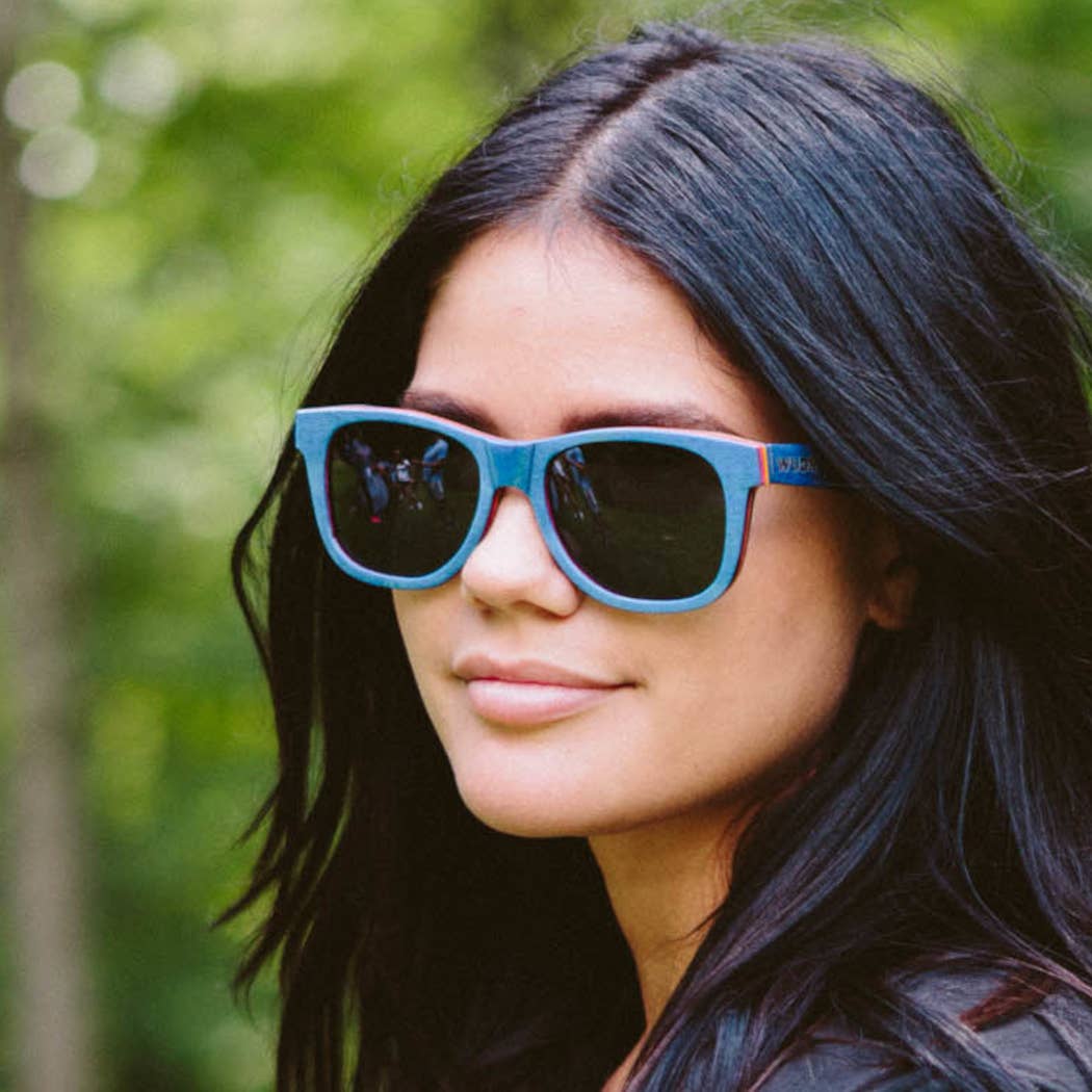 Escalator blue Recycled sunglasses with a blurred green background