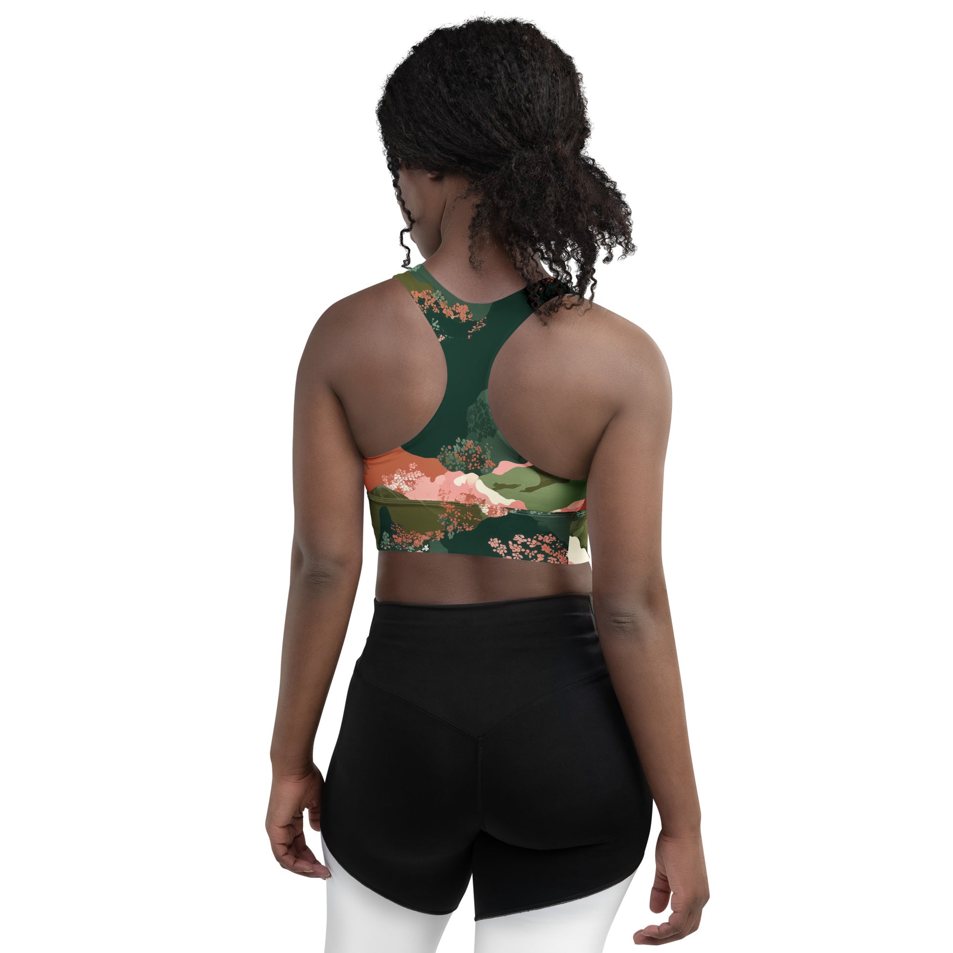 Olive Bloom Woman wearing a green floral sports bra and black shorts on a white background