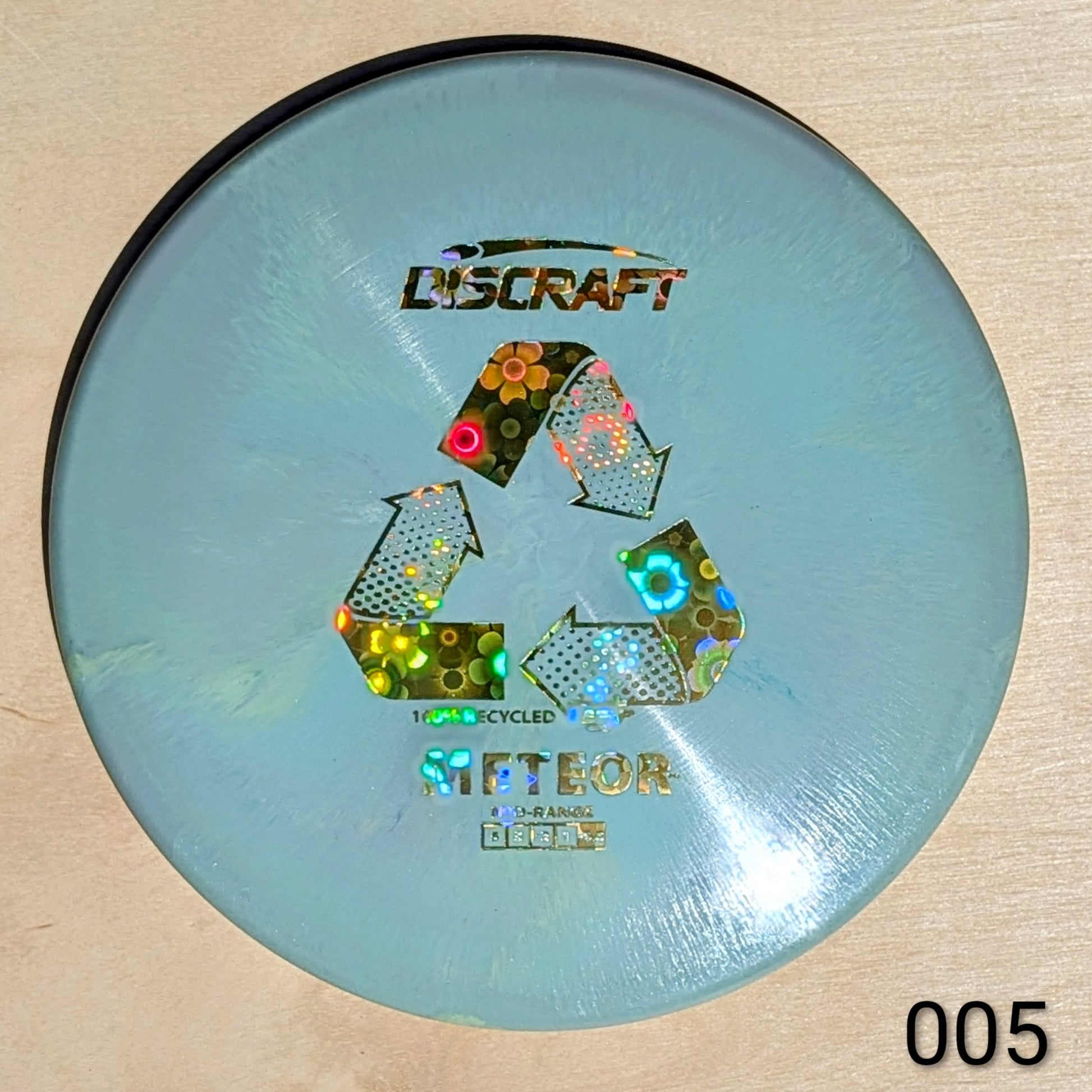 Discraft disc golf disc with recycling symbol on a beige background