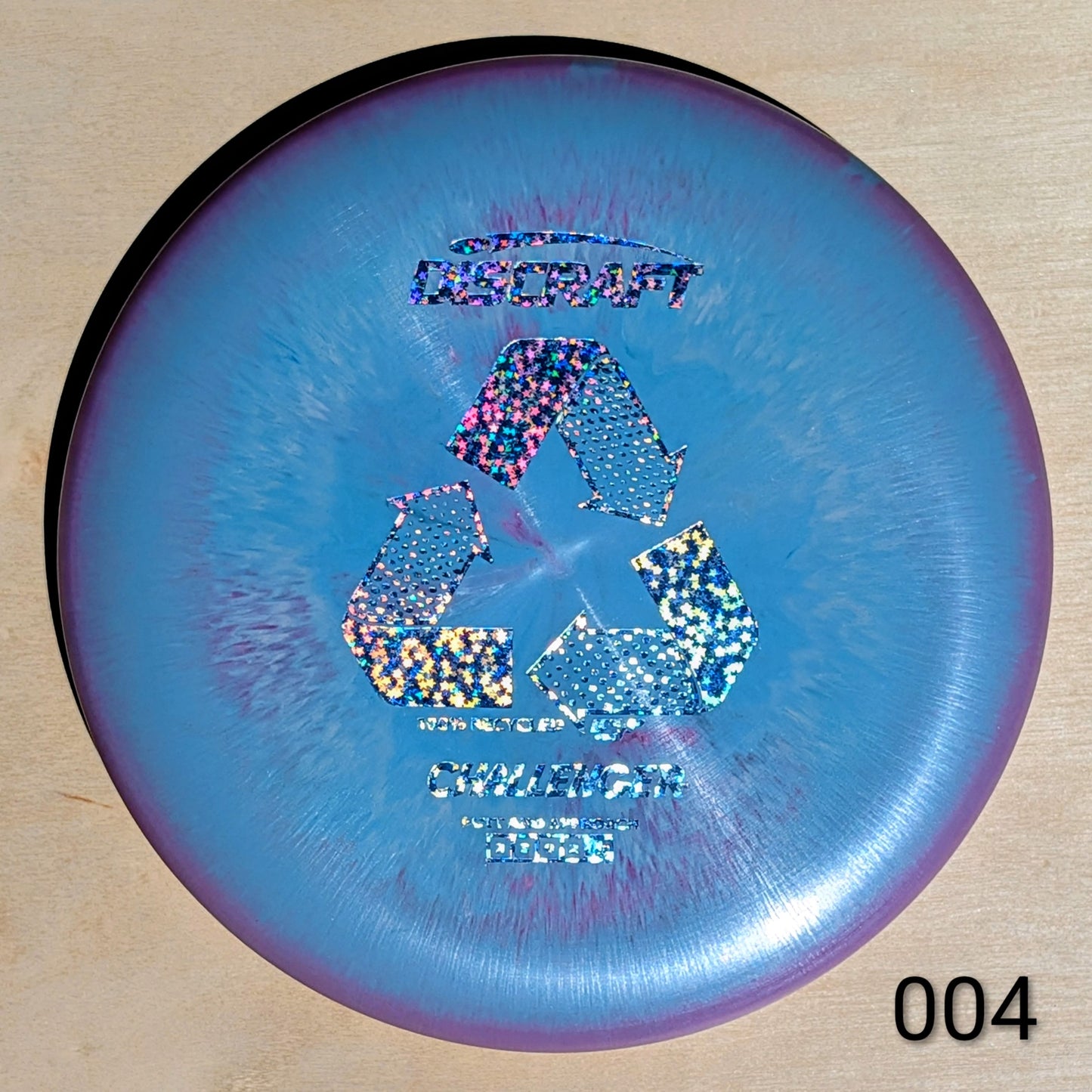 Discraft disc golf disc with recycling symbol on a wooden surface