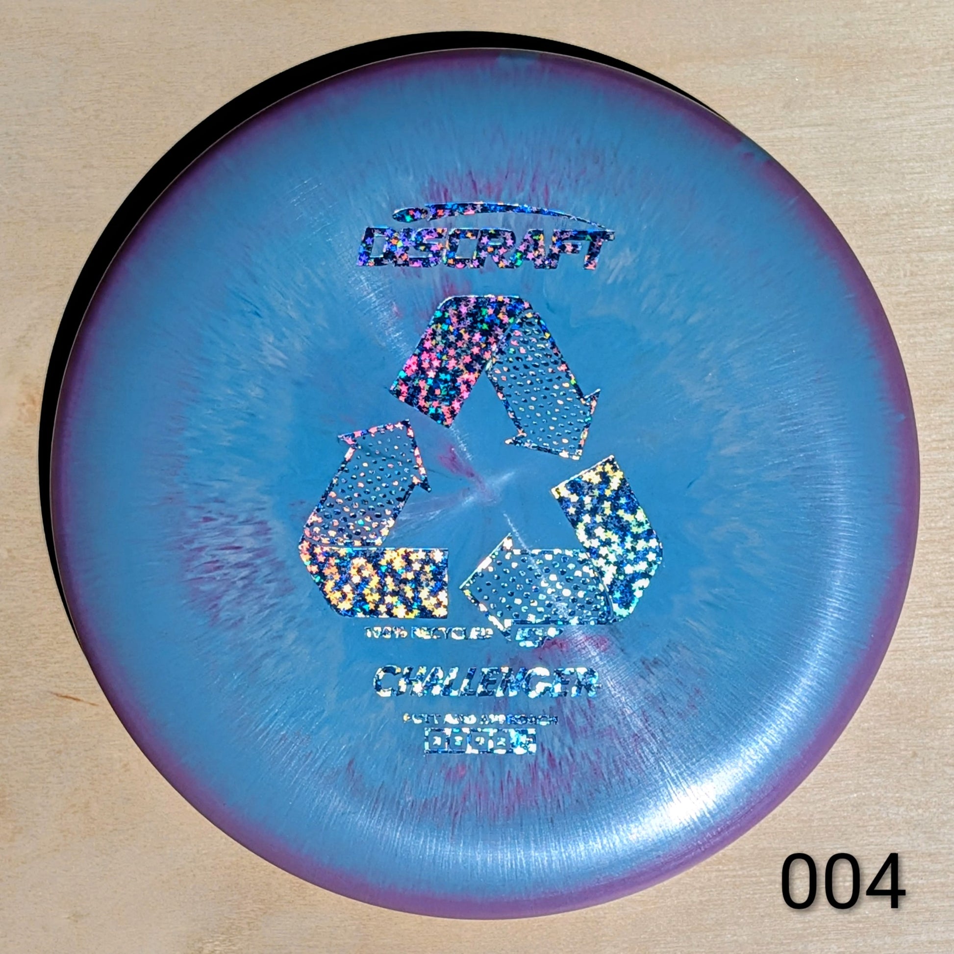 Discraft disc golf disc with recycling symbol on a wooden surface