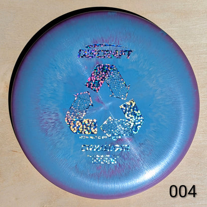 Discraft disc golf disc with recycling symbol on a wooden surface