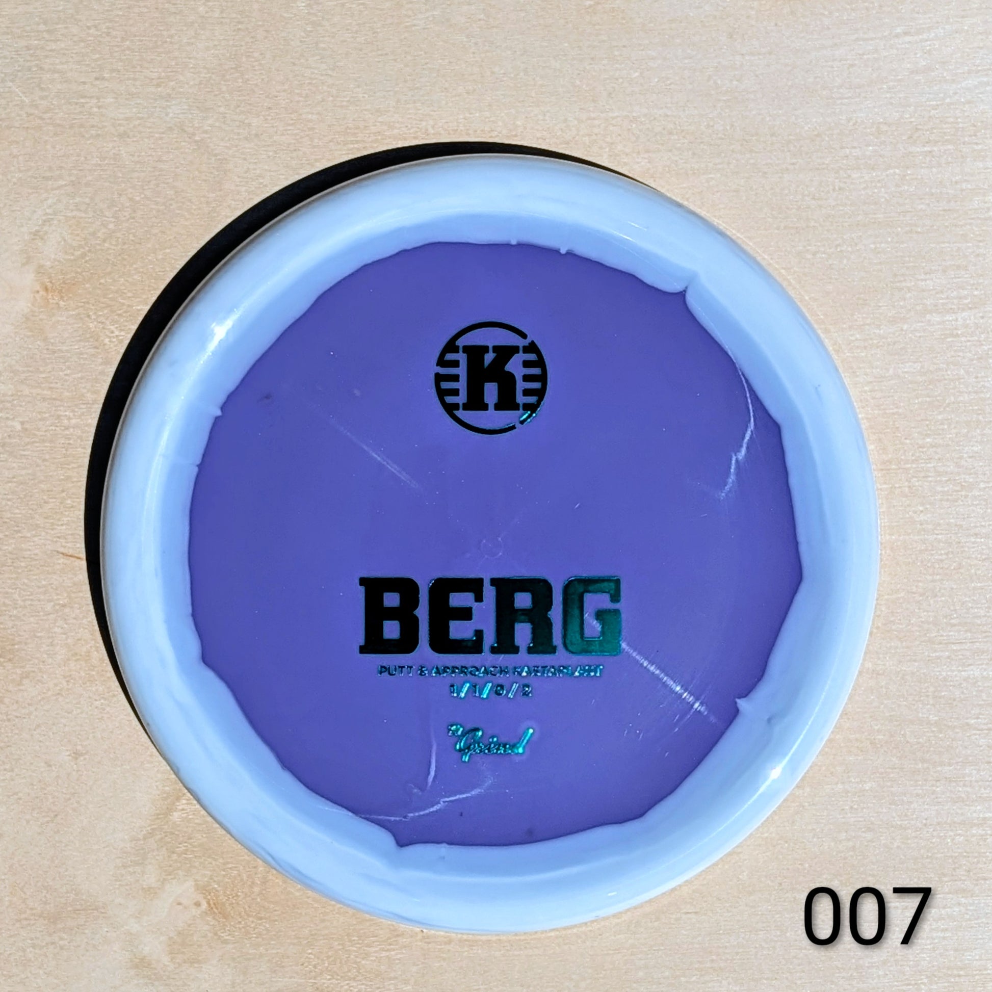 Purple disc with 'K' logo and 'BERG' text on a beige background