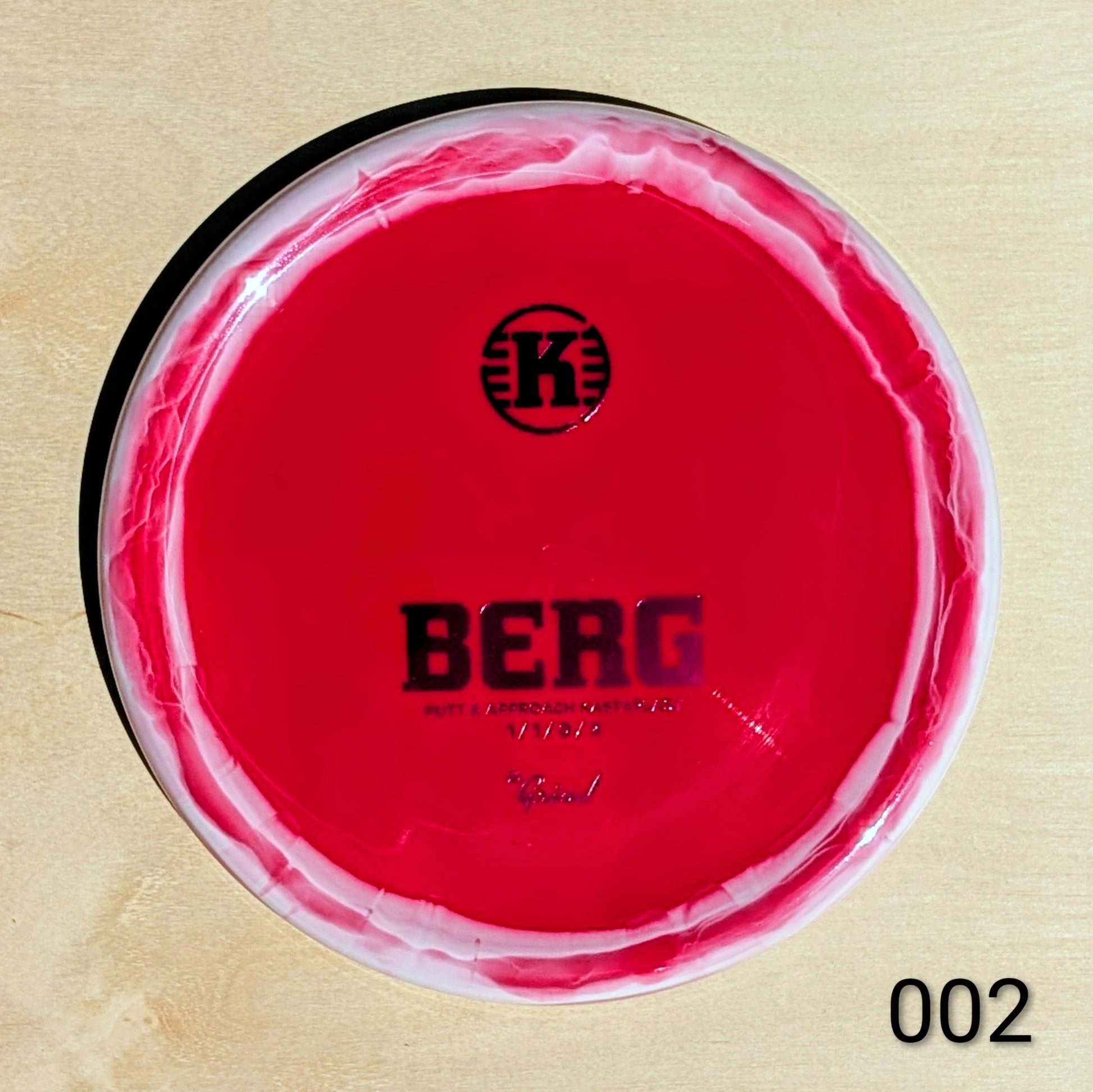 Red disc with 'K' logo and 'BERG' text on a beige background