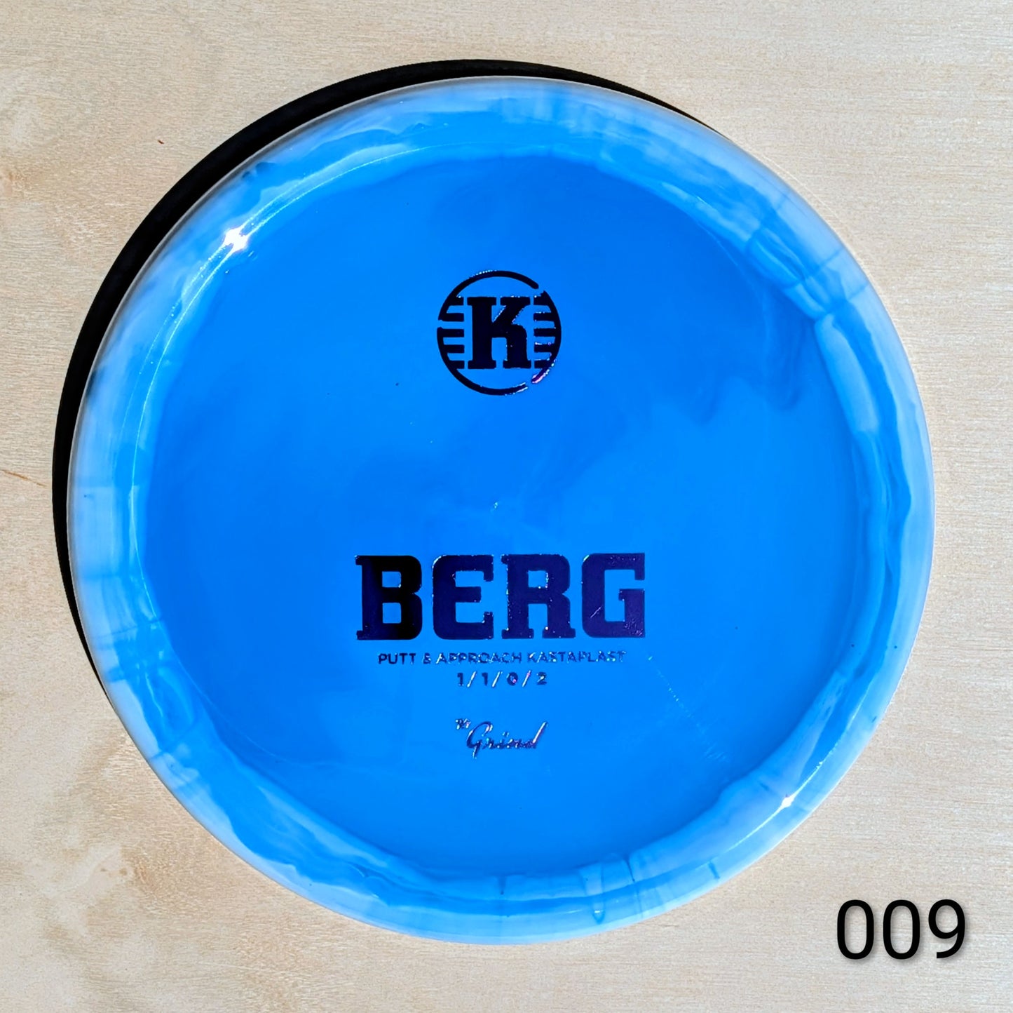 Blue disc with 'K' logo and 'BERG' text on a beige background