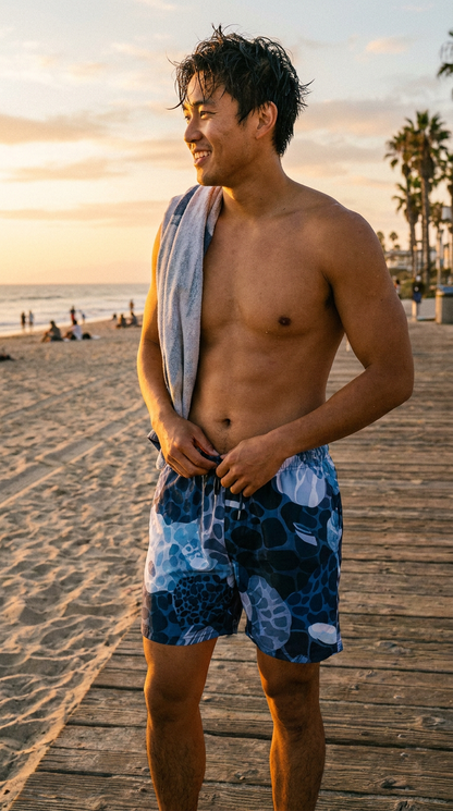 Rockpool Channel man standing on a beach boardwalk with a towel draped over his shoulder, wearing blue swim trunks.