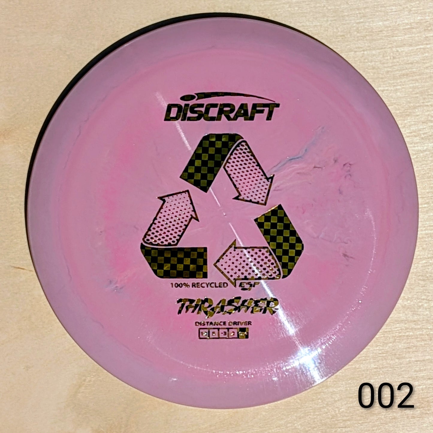 Pink Discraft Thrasher disc golf disc on a wooden surface