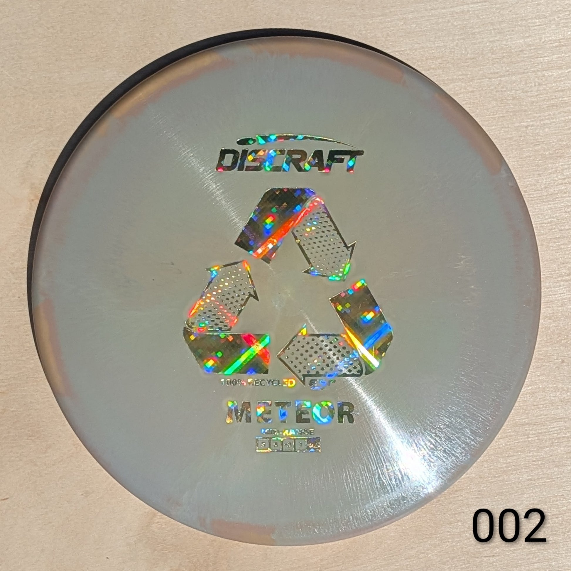 Discraft Meteor disc golf disc on a beige background