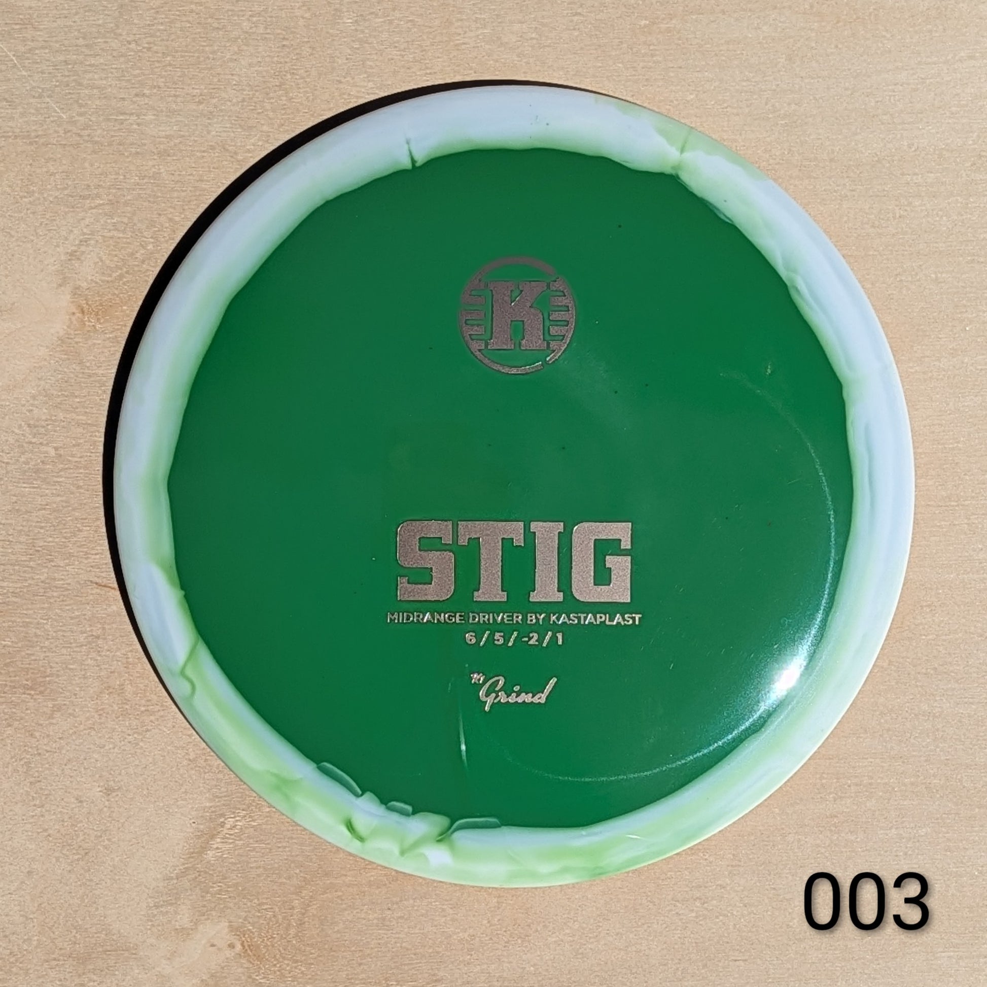 Green disc golf driver with 'K' logo on a beige background
