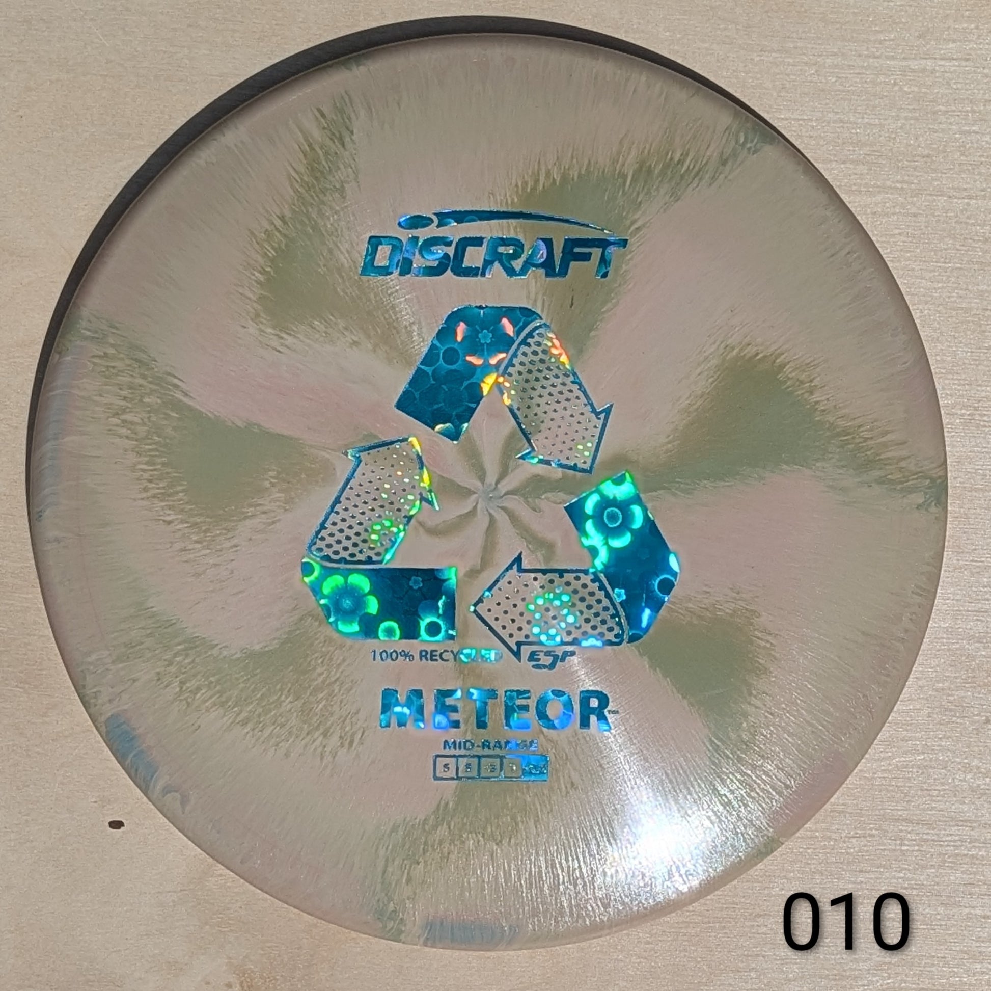Discraft Meteor disc golf disc on a beige background