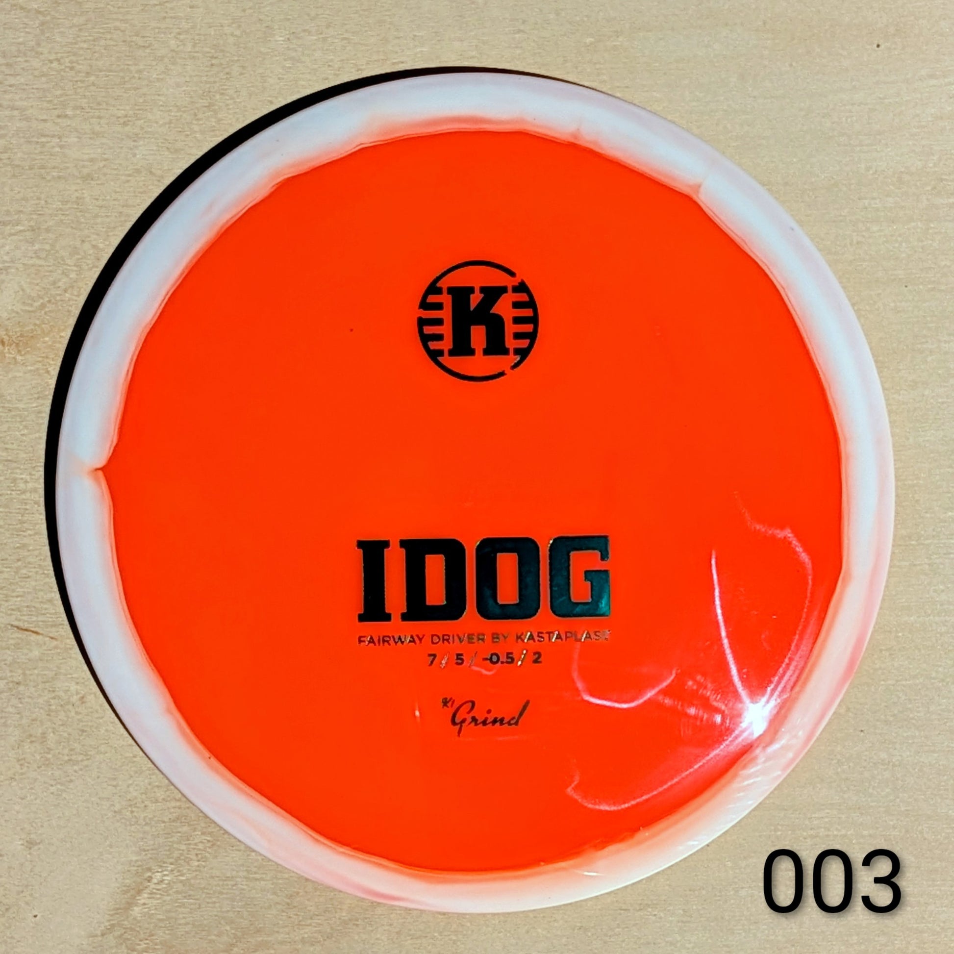 Orange disc golf disc with 'K' logo and text on a beige background
