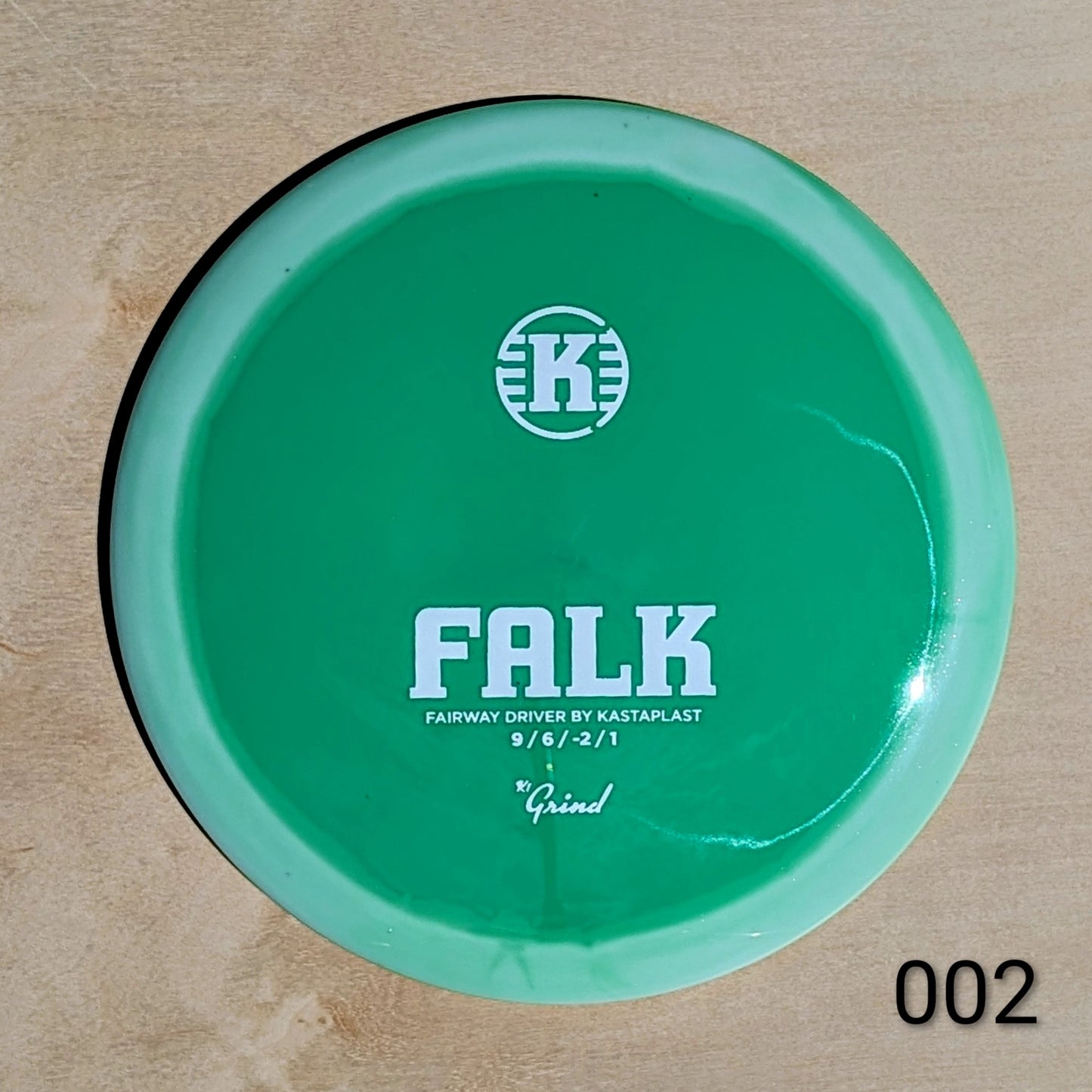 Green disc golf disc with 'K' logo and text on a beige background