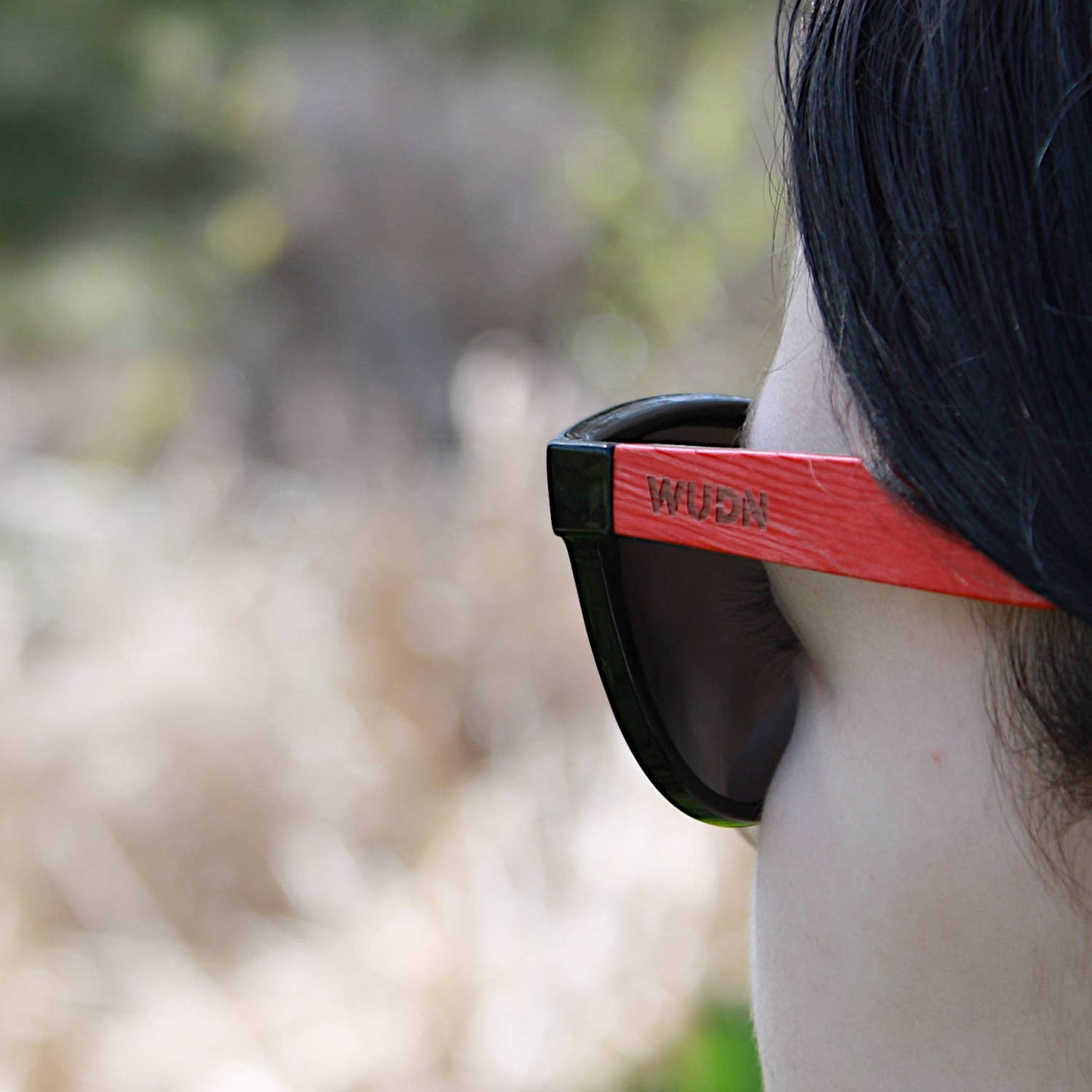 bluntslide red sunglasses with 'WUB' branding, blurred natural background