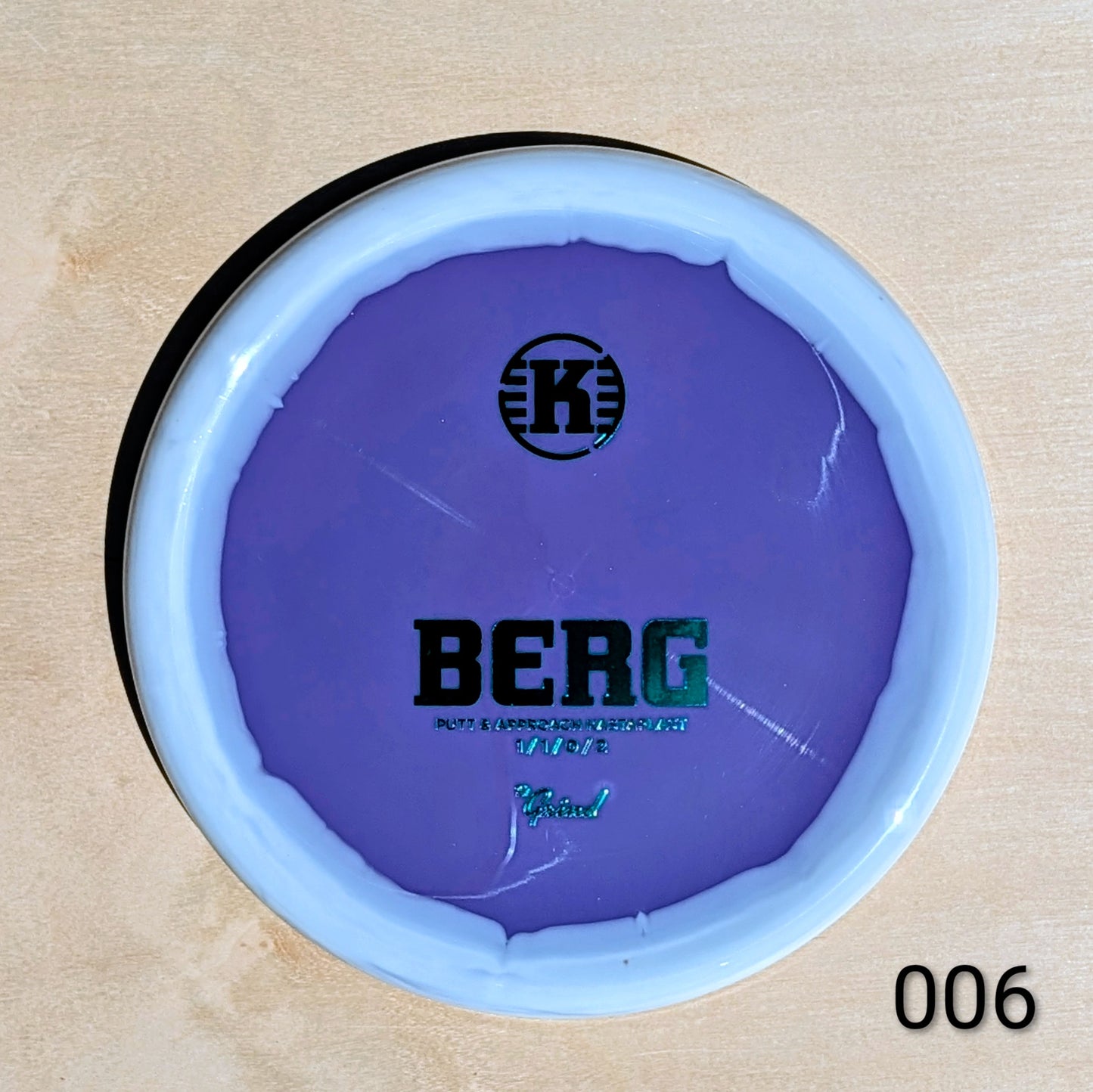 Purple disc with 'K' logo and 'BERG' text on a beige background